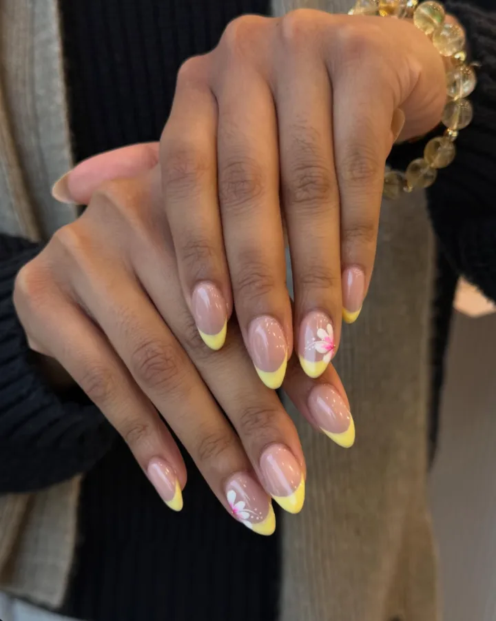 Almond nails with yellow French tips and a pink flower